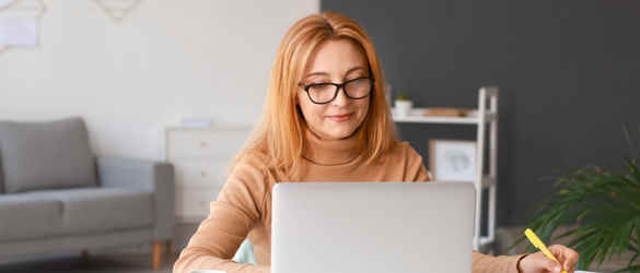 Woman on laptop at home making notes