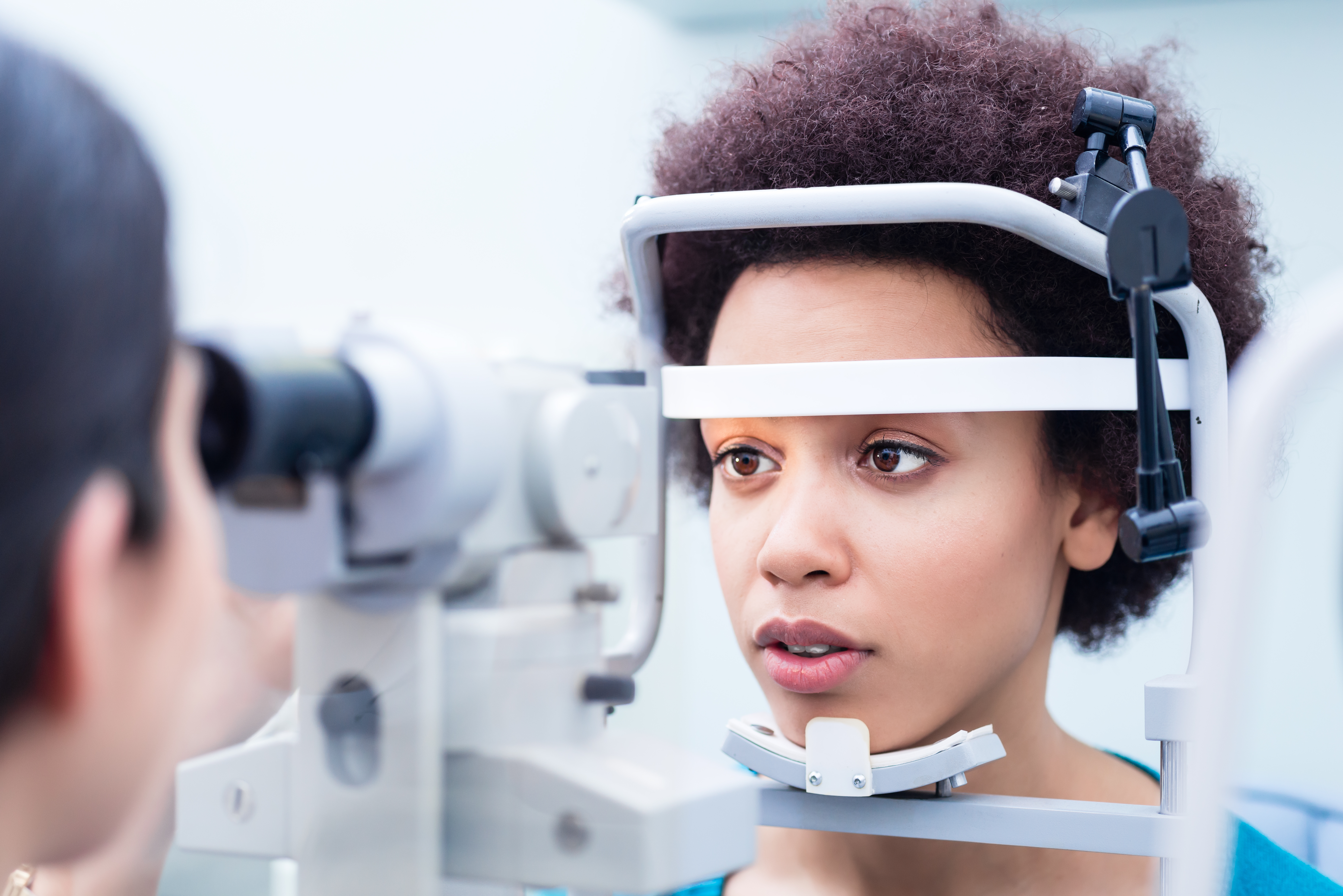 Woman having eye test, resting forehead and chin against machine.