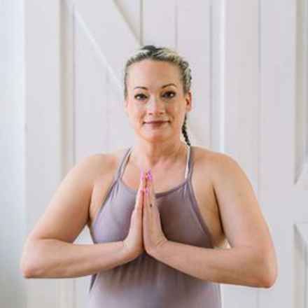Picture of Dawn (in her late 40s) in a yoga studio, holding hands together in yoga pose.