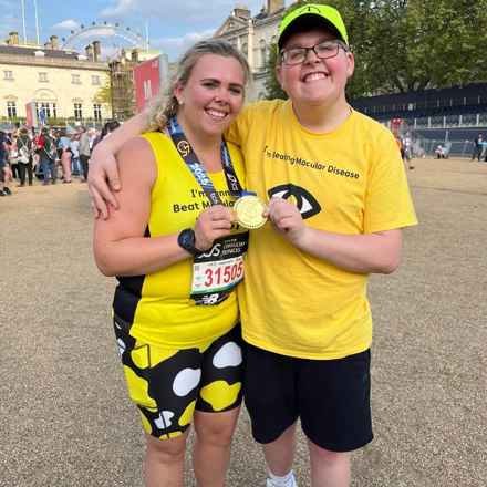 Becky and Richard with their arms around each other and smiling as they hold up Becky's London Marathon medal.